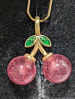 Front view of cherry pendant showing rhodochrosite beads, enamel leaf, silver stem