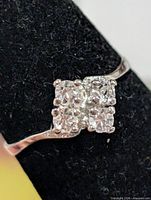 Front view of silver ring showing four clear stones in square cluster