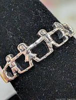 Side view of silver ring showing linked children design