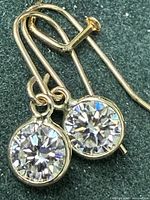 Pair of yellow-gold drop earrings with round clear stones shown close-up