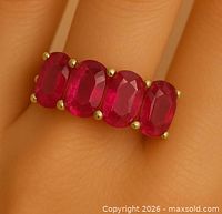 Ring on finger showing four of the oval rubies and prong setting
