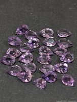 Group of loose pear-cut purple amethyst gemstones on black background