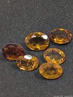 Six oval citrine gemstones on dark background