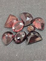 Group of eight loose garnet gemstones showing assorted cuts