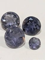 Four round faceted iolite gemstones on white background