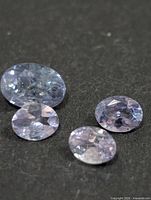 Four faceted oval tanzanite gemstones on black background