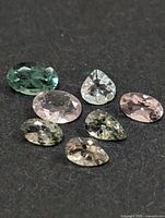 Seven loose faceted tourmalines in assorted colours on dark background