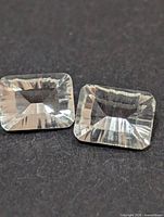 pair of rectangular white topaz gemstones on dark background