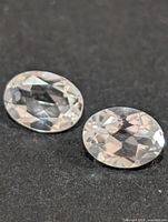 Two oval faceted white topaz gemstones on dark background