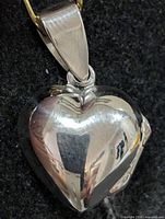 Front view of polished silver heart locket with bail