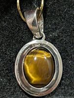 Front view of pendant showing tiger eye cabochon and silver frame
