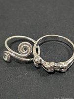 two silver-tone rings side by side on dark background