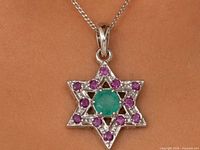 Front view of silver star pendant on chain showing emerald centre and surrounding rubies