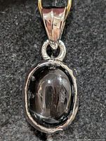Front view of sterling silver pendant with oval black onyx cabochon