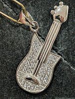 front view of silver guitar pendant showing cubic zirconia detail