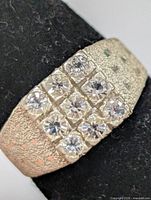 Top view of silver ring showing 12 clear stones in grid