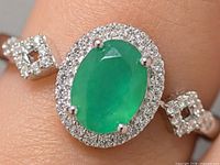 Earring on finger showing oval green onyx, CZ halo and side accents