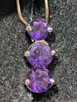 Front view of silver pendant showing three round purple amethysts