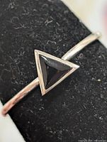 Close-up of triangular black onyx stone in silver bezel
