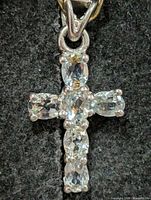 Front view of silver cross pendant with six oval blue topaz stones