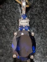 Front view of pendant showing main oval created sapphire and accent stones