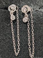 front view of earrings on display showing cubic zirconia settings and chain drops