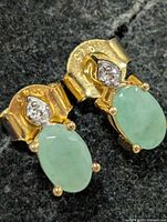 Front view of earrings showing green cabochon stones and clear stone accents