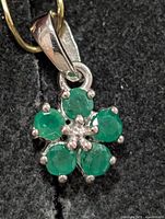 Front view of silver pendant with emerald flower design