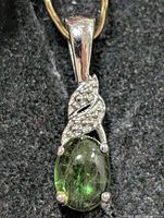 Front view of sterling silver pendant with green cabochon and clear stone accent