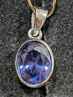 Front view of oval faceted iolite pendant in silver bezel setting