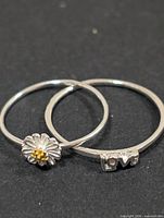 Two silver rings, daisy and LOVE designs