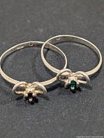 both silver rings showing bow settings and stones