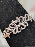 Front view of silver scroll ring on display mandrel