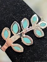 Oblique close-up of ring front showing leaf design and turquoise inlay