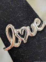 Front view of silver-tone ring showing "love" script design