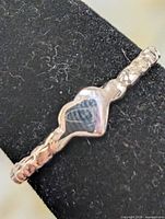 Textured silver ring on mandrel, side view showing heart bezel and cabochon