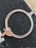 Ring viewed from back showing full circular band and heart charm attachment
