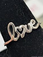 Front view of silver script love ring on display stand