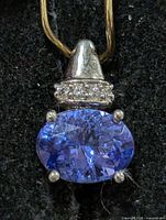 Front view of silver pendant with oval tanzanite and accent stones