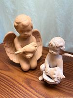 Both angel figurines side by side on wooden surface