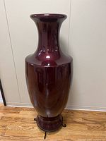 Front view of tall burgundy fiberglass vase on metal stand