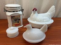 Group of four white glass and ceramic kitchen collectible pieces on wood surface