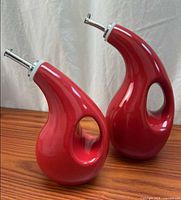 front view of both red ceramic cruets on wood surface