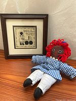 Doll lying beside framed print showing size relation and overall condition