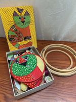 Overview of kit: pattern box, red hoop on fabric panel, wooden hoops
