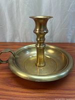 overall view of brass chamberstick showing stem, drip pan, thumb rest