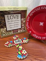 Group shot of boxed wall plaque, cross ornament, and red plate