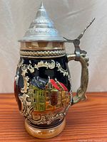 Full view of ceramic beer stein showing relief Munich motif and pewter lid