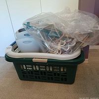 All items grouped: green basket holding grey bins and bag of hangers, white basket visible