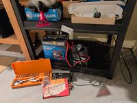 Battery booster pack with box and cables on shelf